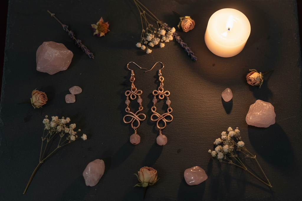 Moody altar flat lay of Madagascar Rose Quartz copper infinity loop earrings