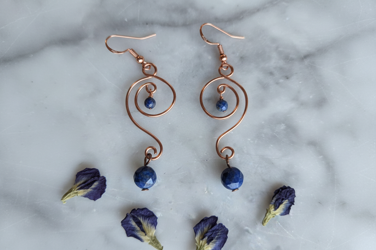 Lapis Lazuli copper S-curve wave earrings vertical flat lay on white marble