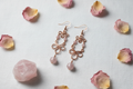 Flat lay of Madagascar Rose Quartz copper infinity loop earrings on white linen
